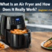 Modern black air fryer cooking crispy chicken nuggets, salmon, and vegetables on a kitchen countertop, showing how an air fryer works using hot air circulation